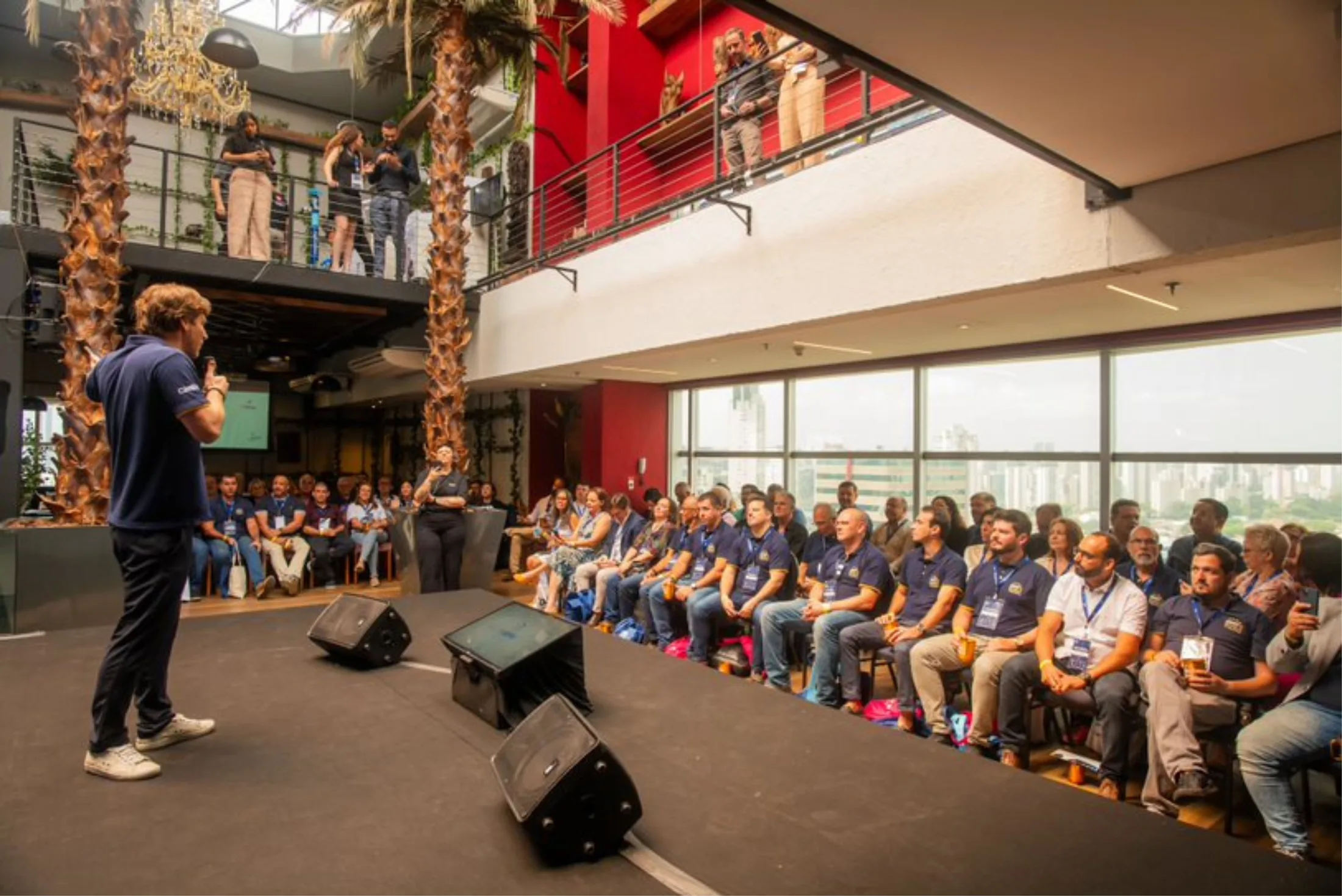 Palestrante no palco diante do público em um evento no Rooftop Berrini